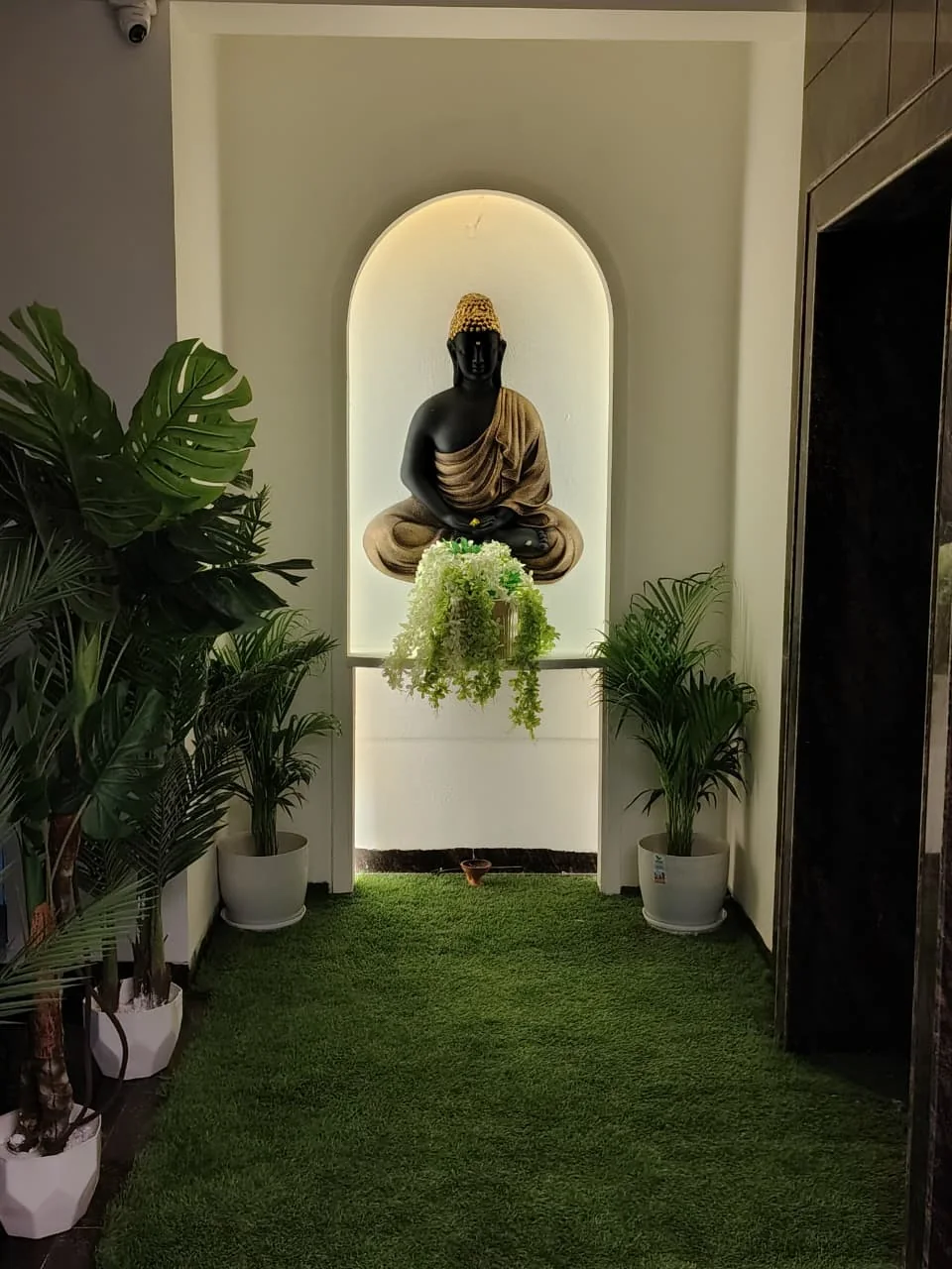 Buddha-inspired illuminated entrance detail with green plants at Body Spa and Wellness